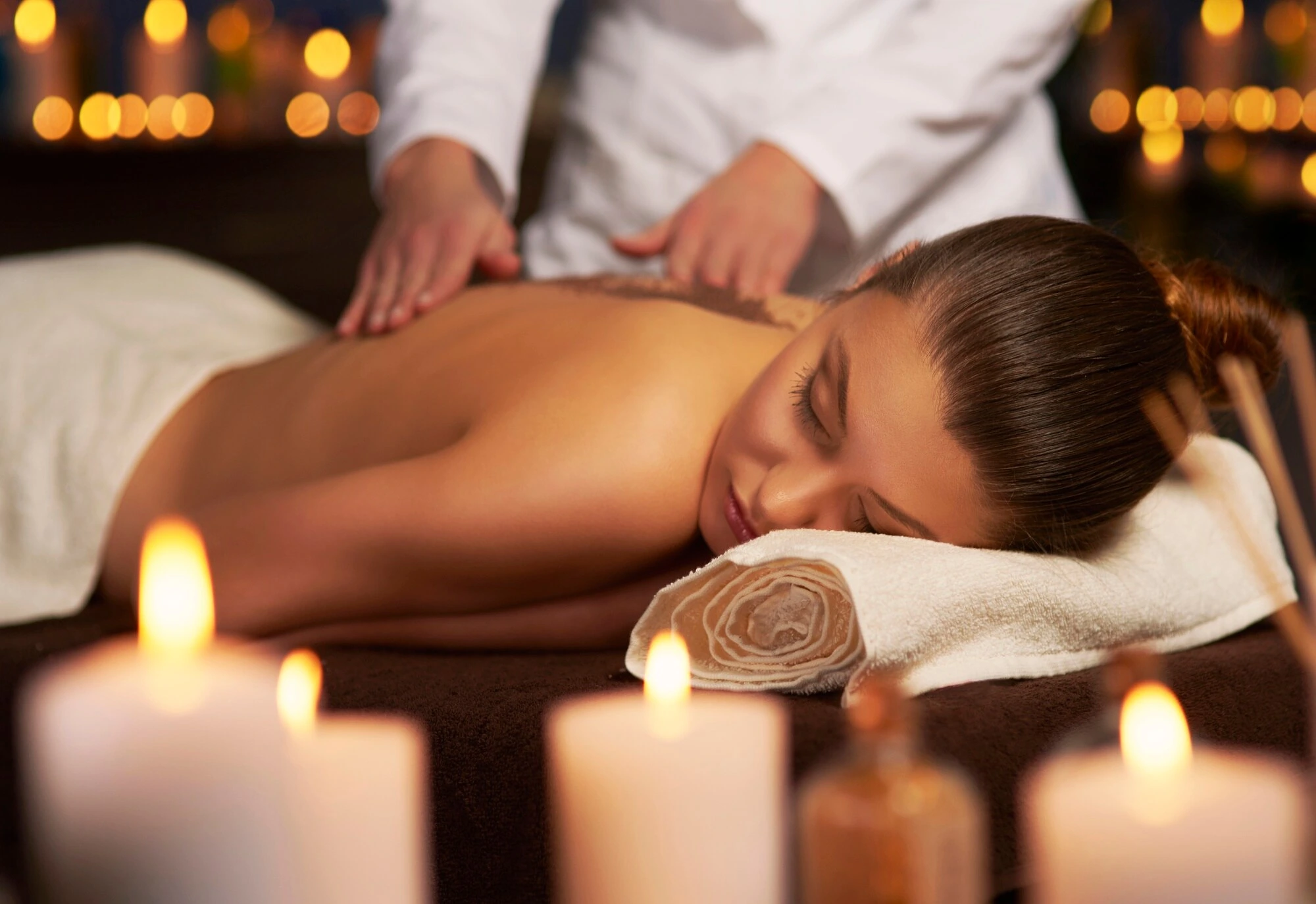 A registered massage therapist working on a client's back among candles