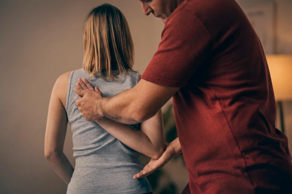 A practitioner assessing the movement of a client's shoulder and spine from behind